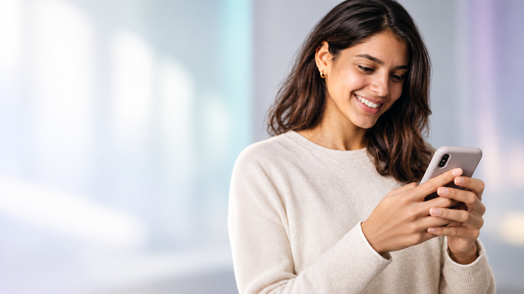 Mujer sonriendo mientras usa su teléfono para comunicarse